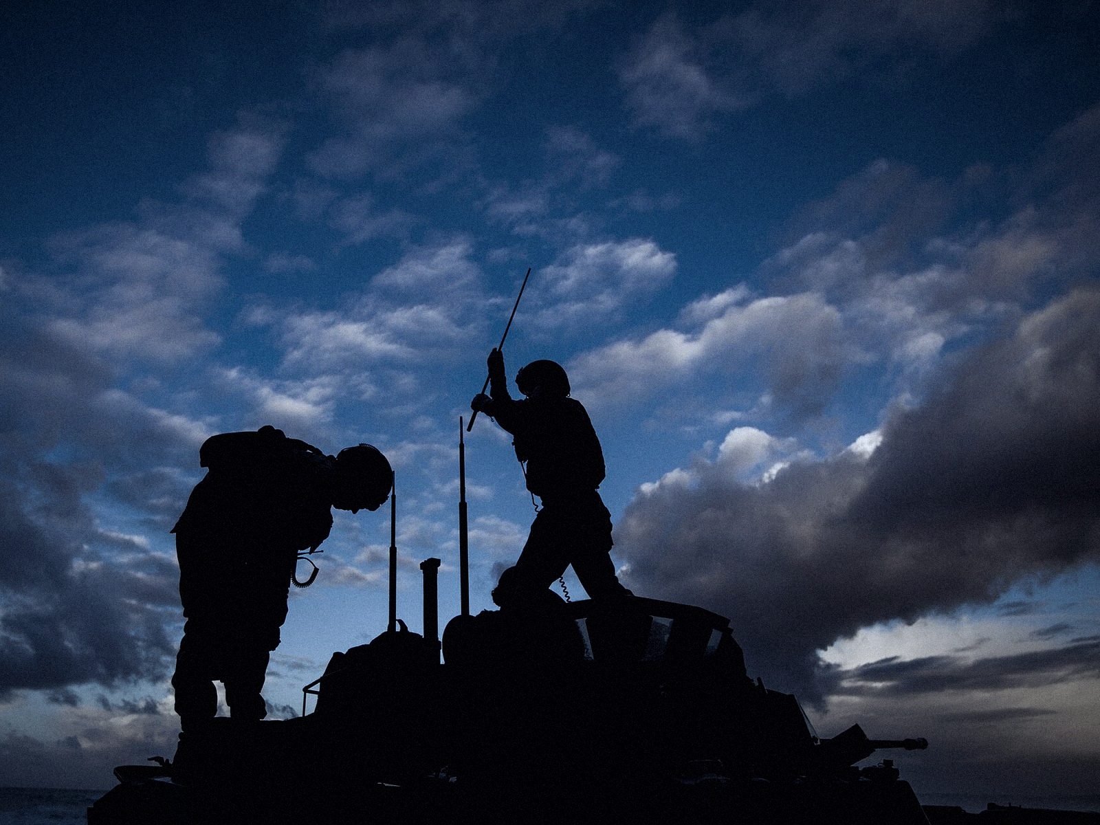 Militaires installant une antenne de communication sur un véhicule au crépuscule